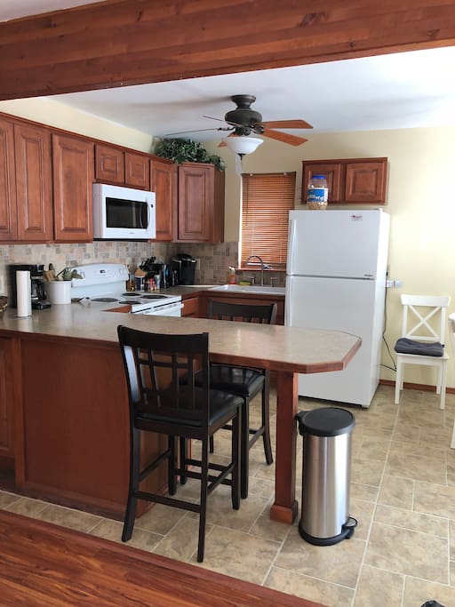 Modern kitchen with brand new appliances, including refrigerator, dish washer, range and microwave. Completed with coffee maker, kettle, double sink and breakfast bar.