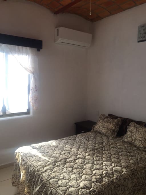 recamara con una cama matrimonial, ventilador y aire acondicionado.