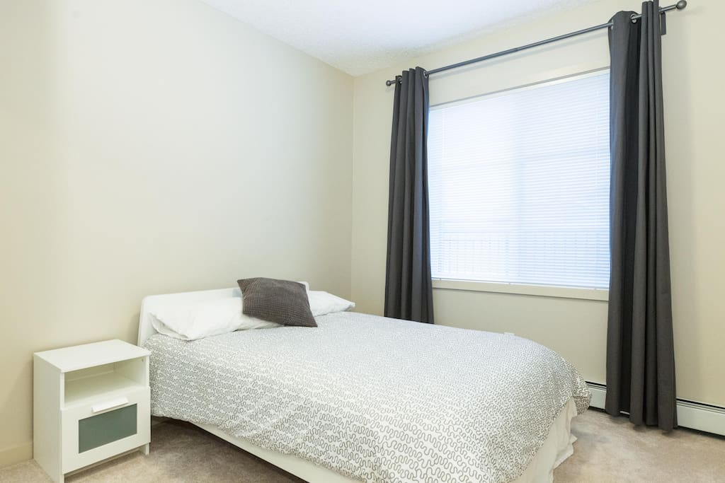 Guest room features new bed, large window overlooking balcony, and full mirrored closet.