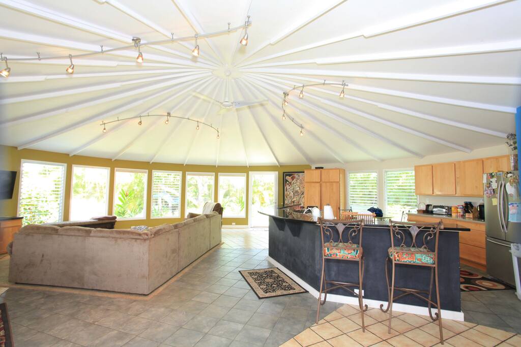 large open air design of living room looking out to tropical front yard with lots of windows