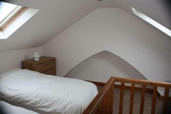 Spavaća soba u potkrovlju s 2 kreveta za jednu osobu i prostorom za putni krevetić ili madrac na napuhavanje.