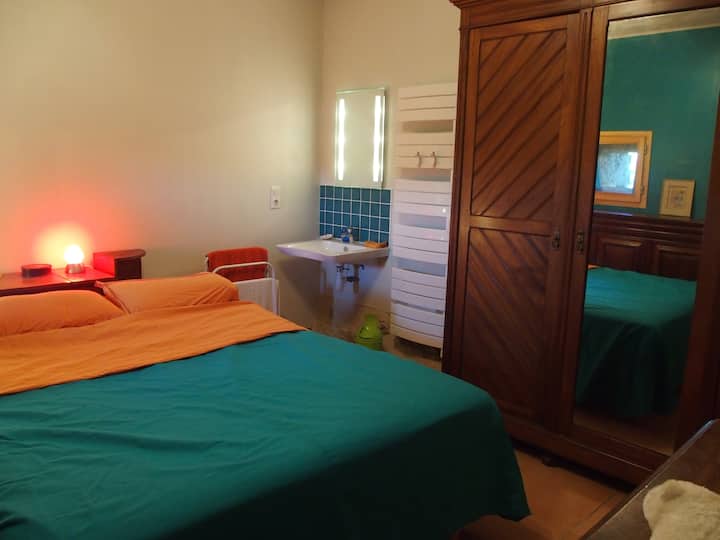 Prízemná spálňa pre ľudí s obmedzenou pohyblivosťou, manželská posteľ, umývadlo na rohu, široký prístup, 2 malé okná na severnej strane, časť úložiska je obsadená osobnými vecami.