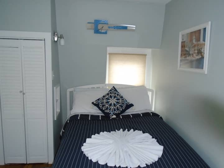 Dormitorio blanco con cama de tamaño completo con capacidad para 2 personas.
