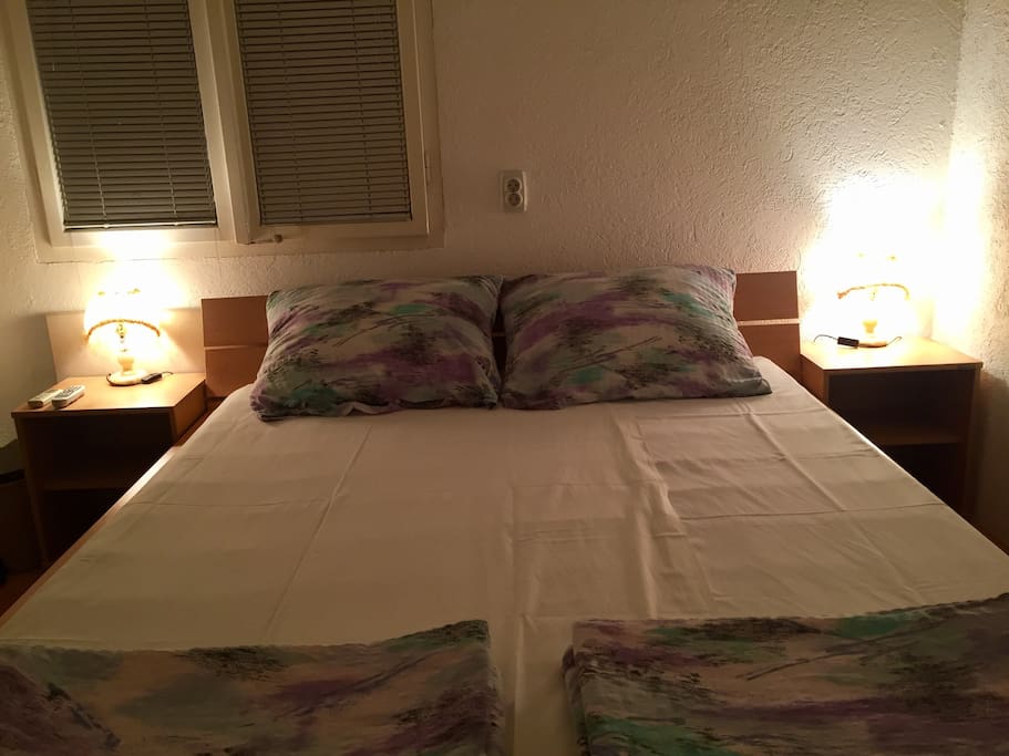 Double bed with desk lamps on.