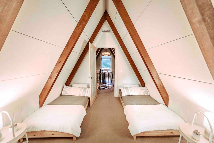 Third floor bedroom with two twin beds and balcony overlooking Silver Lake.

Photo @dirtandglass