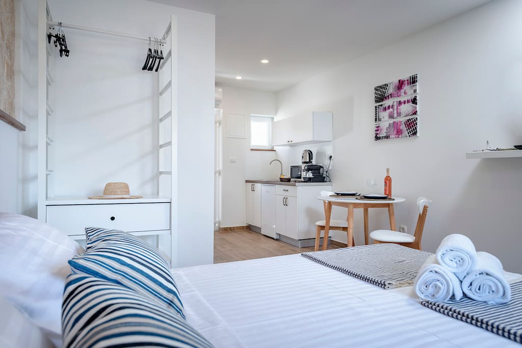 Double bed with the kitchen area and a dining table, newly renovated inside an old Hvar's stone house. The room has A/C and satellite smart TV