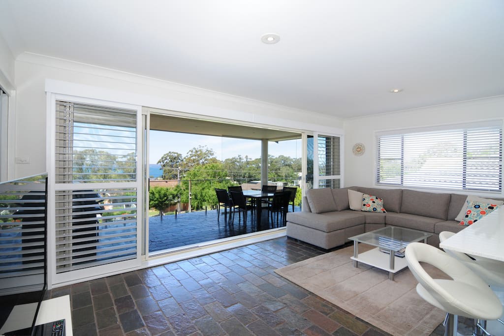 Living room and kitchen with sliding plantation shutters, air con, large screen TV with Foxtel and great view out across Jervis Bay