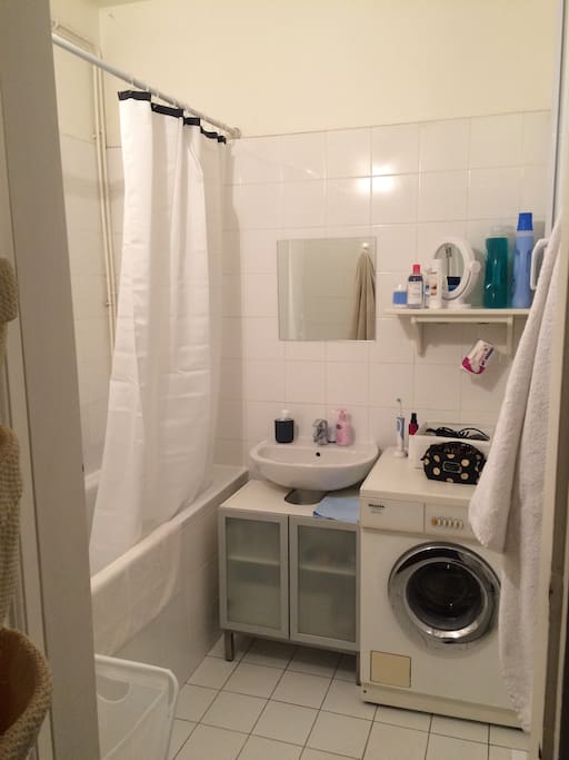 Salle de bain avec fenêtre, baignoire et machine à laver.