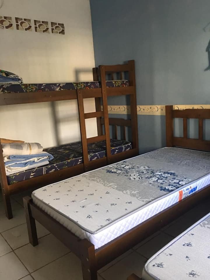 dormitorio inferior con litera y dos camas individuales y ventilador de techo