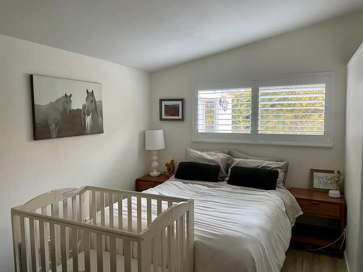Dormitorio con cama tamaño queen y cuna. La cuna está sobre ruedas y se puede enrollar fácilmente a una habitación diferente si lo deseas.