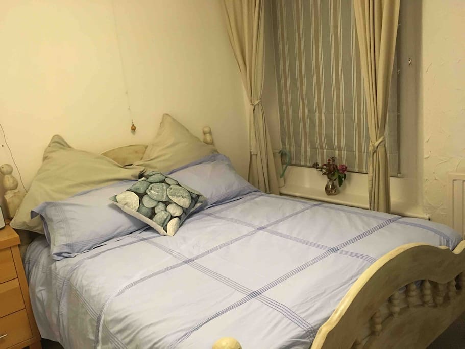 The guest bedroom with a double bed, bedside cabinet and shelves.