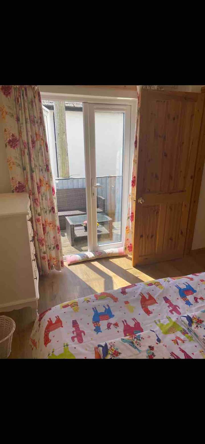 La acogedora habitación doble de la planta baja se abre al soleado patio delantero y tiene el baño adyacente.