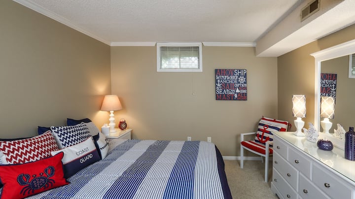 חדר שינה בגודל קינג סייז עם שידות לילה, מנורות ושידה עם מראה.