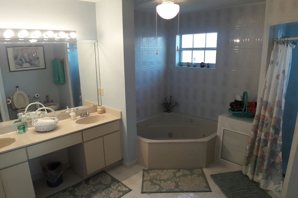 This extra large bathroom features warm marble units and modern white sanitary ware. Huge shower and tub accompanied by two sinks, a large mirror and a window to brighten the room.
