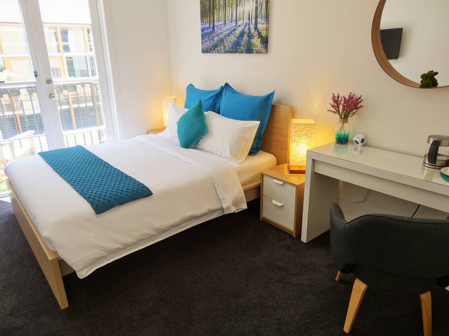 Your private room with lots of natural light, blockout blinds, balcony for the warmer months, a comfy queen sized spring bed, built-in robes, a writing desk and tub chair, along with tea and coffee making facility.