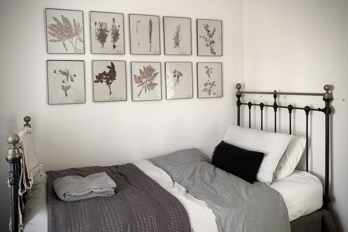 Bedroom 4 with a cast iron full size bed with pressed sheets and plants.