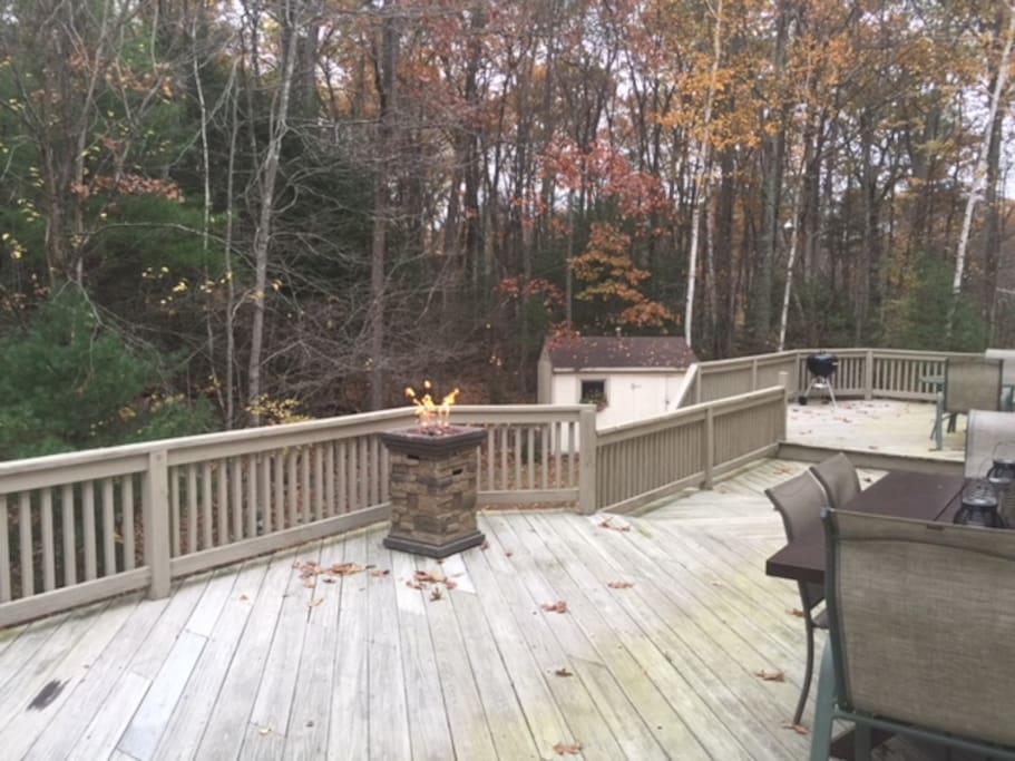 Large back deck overlooking a secluded wooded area with seating, table and charcoal grill available for use.
