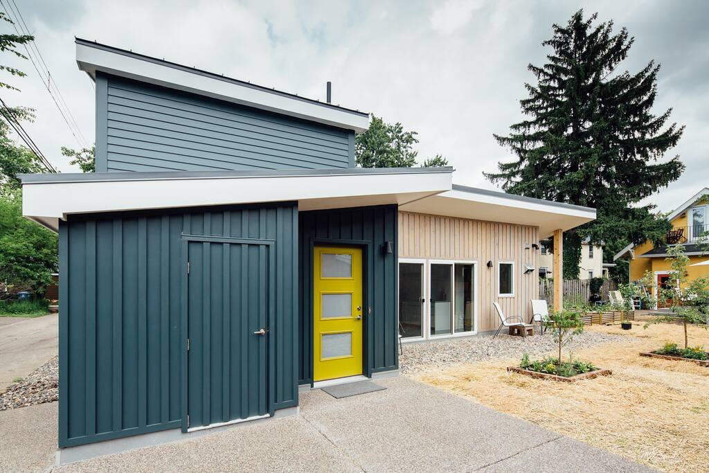 Brightly colored entry door and parking area for 1 midsize car. Mustard colored house to the very right in picture is where I live.