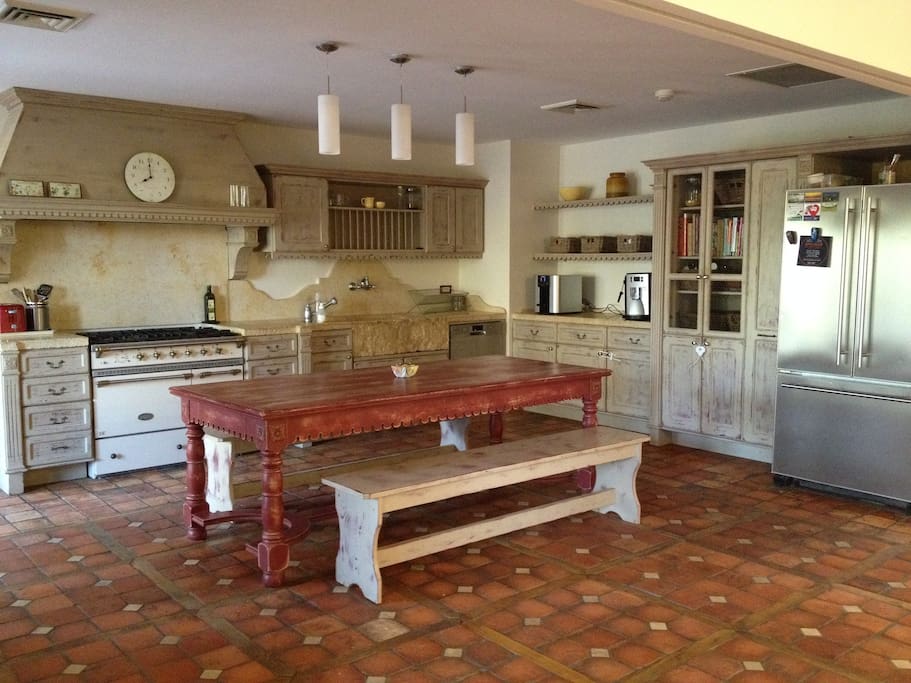 Well-equipped custom kitchen with two ovens, hand-carved natural stone sink and doors to backyard.