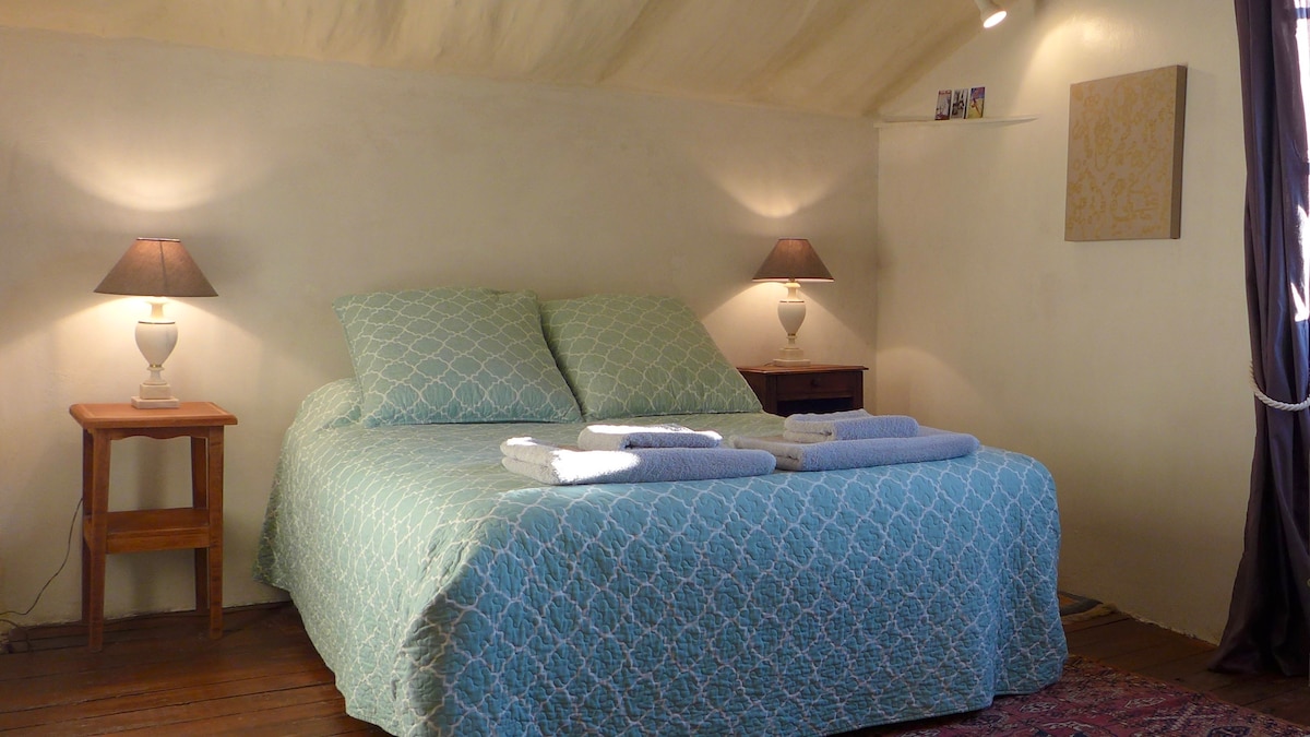 Apartman s bračnim krevetom na gornjem katu s bračnim krevetom, stolićima i svjetiljkama.