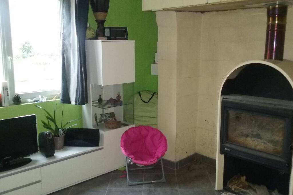 salon avec la télévision et le poêle. Vue sur le jardin.