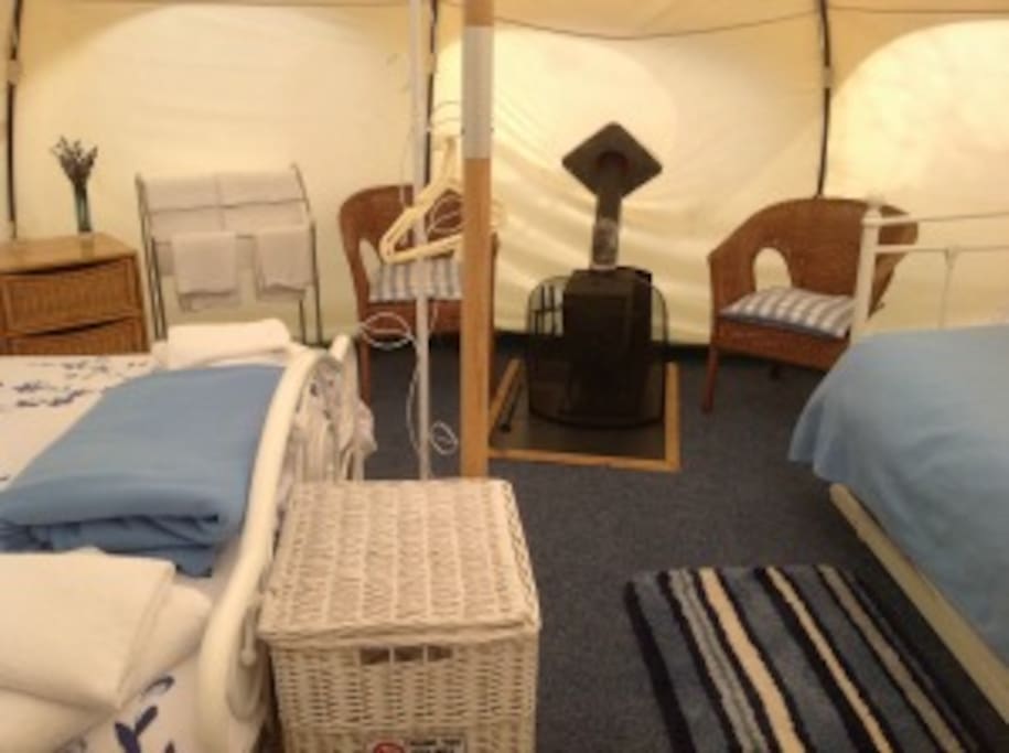 Inside Bluebell tent, double bed on the left, edge of day bed on the right and log burner in the middle.