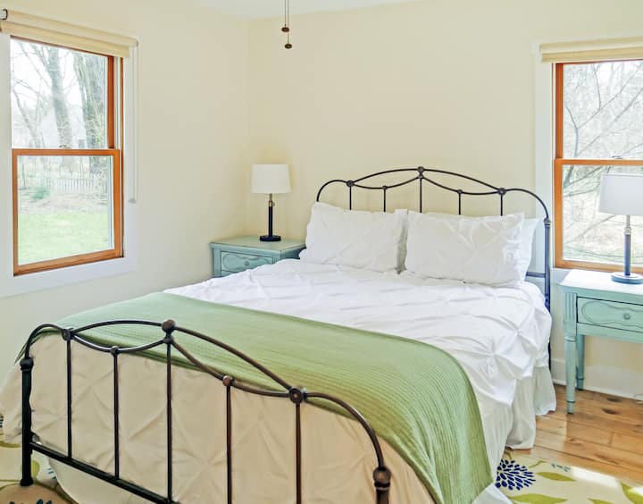 Trek je terug in de eerste slaapkamer, waar luxe en comfort samenkomen met een queensize bed met een premium Simmons Beautyrest Signature Select-matras, geflankeerd door twee nachtkastjes, een plafondventilator en georganiseerd met Martha Stewart's kastsysteem.