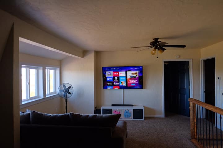 Sala de TV en la planta superior con sofá modular y puf.