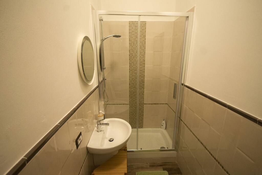 Bagno con finestra e ampia doccia decorata con mosaico.