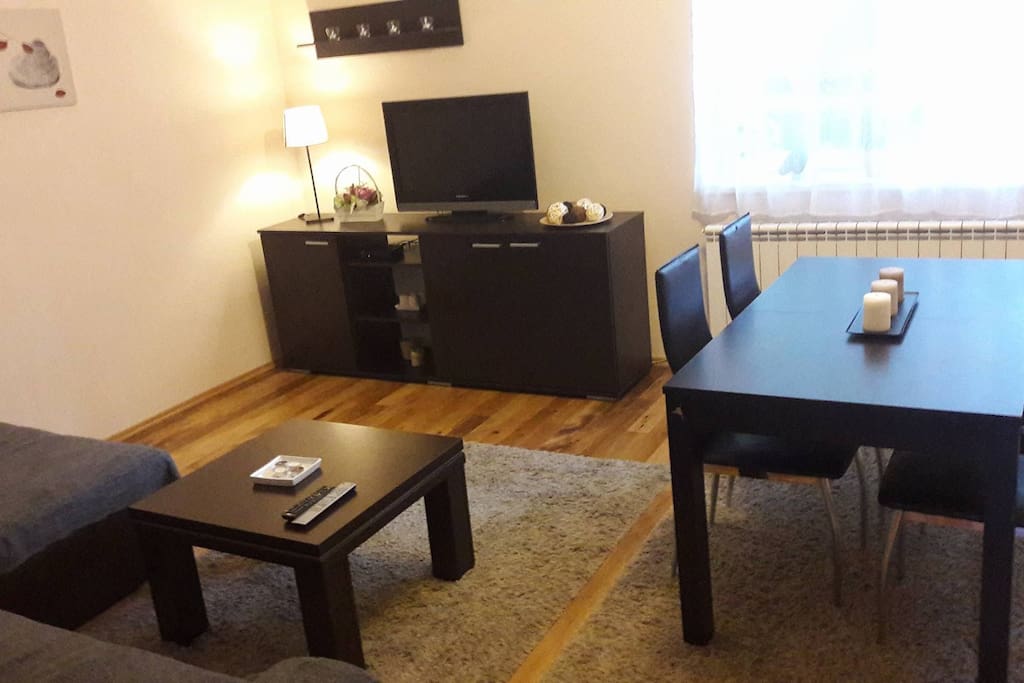 Sitting room with flat-screen TV and dining table.