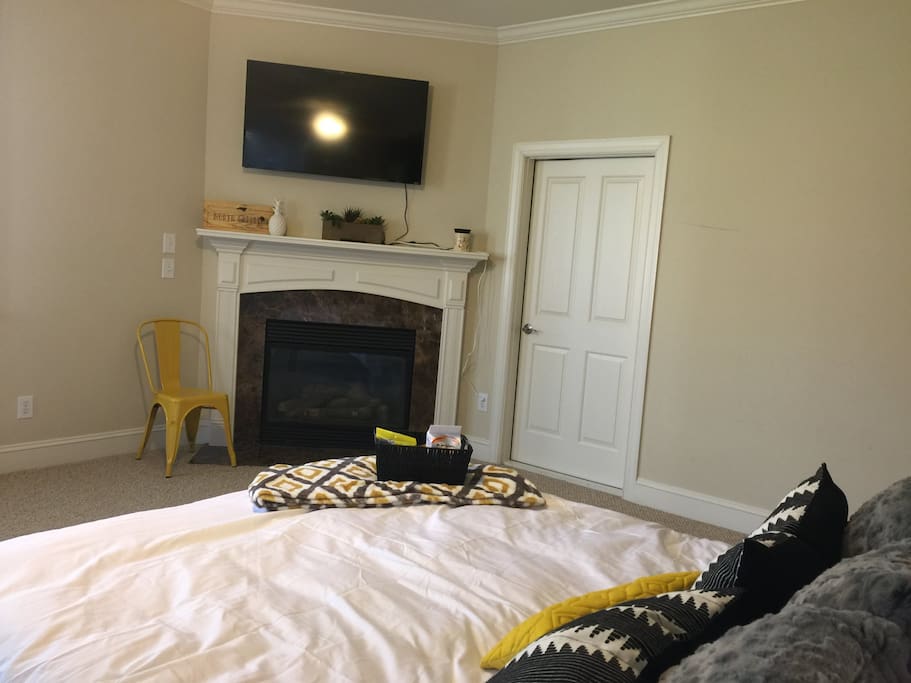 From the bed, there is a tv over the fireplace.