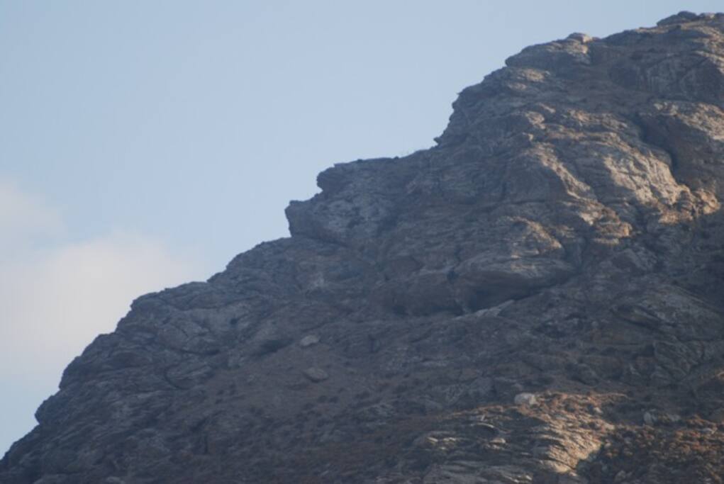 το βουνό πάνω απότο λιμάνι των Καταπόλων. Διακρίνεται το προφίλ ενός γέροντα που κοιμάται. Πίσω από το σημείο αυτό σε ανασκαφές έχουν βρεθεί τα καλοκαιρινά θέρετρα του βασιλειά Μίνωα.-
the mountain above the port of Katapola. It is visible the profile of an old man which sleeps. Behind this point in excavations they have revealed the summer resorts of Basel Minos.