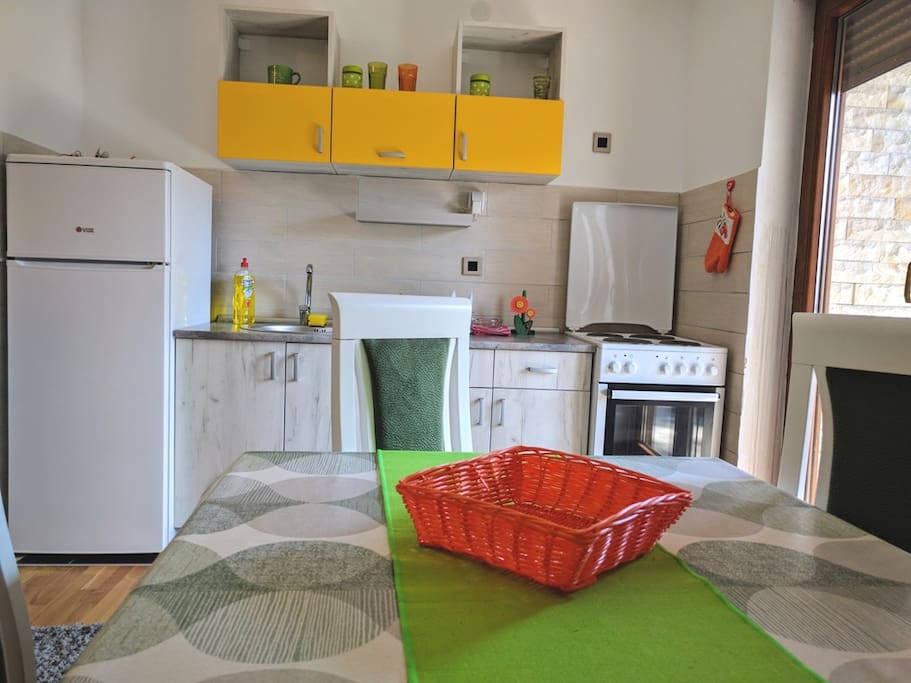 Fully equipped kitchen with stove, dishes and fridge