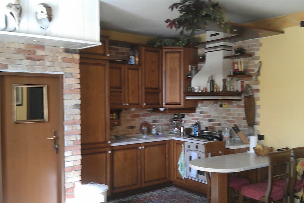 Angolo cucina con Frigorifero, Freezer, fuochi a gas. Porta di accesso al garage e zona lavatrice.