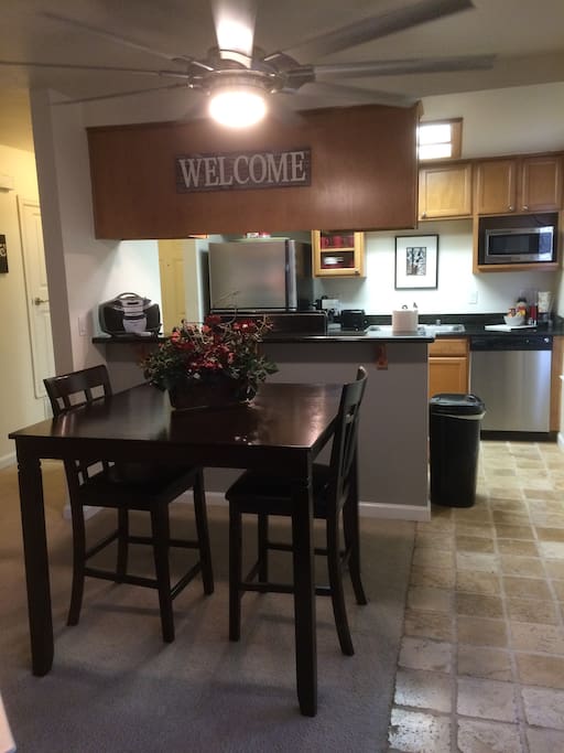 Dining room has a new table set with four bar height padded chairs. Above the table is a large silver fan resembling an airplane propeller to accommodate the large 3-D Aircraft Wall Art in the living room.