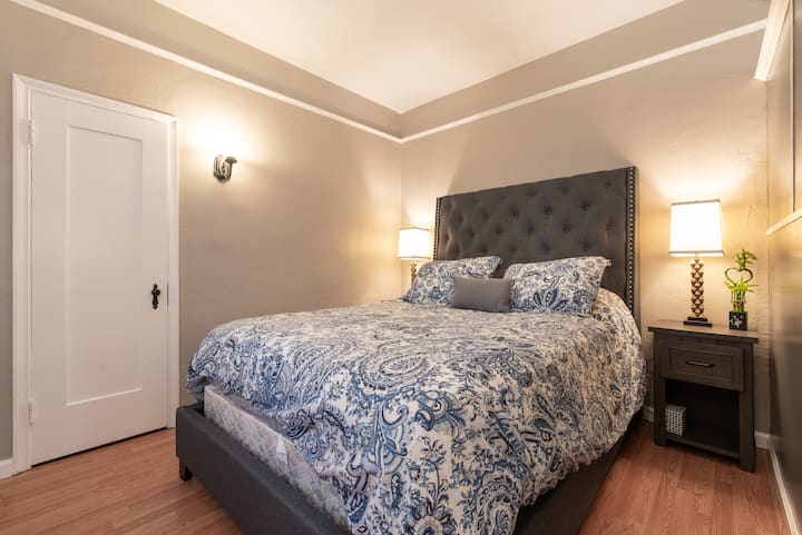 Cama tamaño queen, vestidor, plancha, tabla de planchar, cesta de lavandería y perchas.
