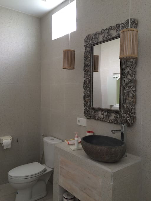 Ensuite bathroom with tiled non-slip floor, rain water shower, reclaimed antique teak windows and hand carved stone basins.