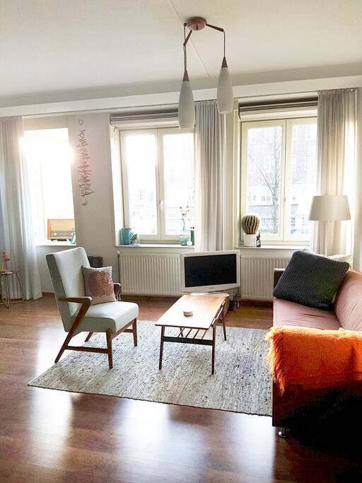 Bright living room on the corner of the apartment block with lots of windows.