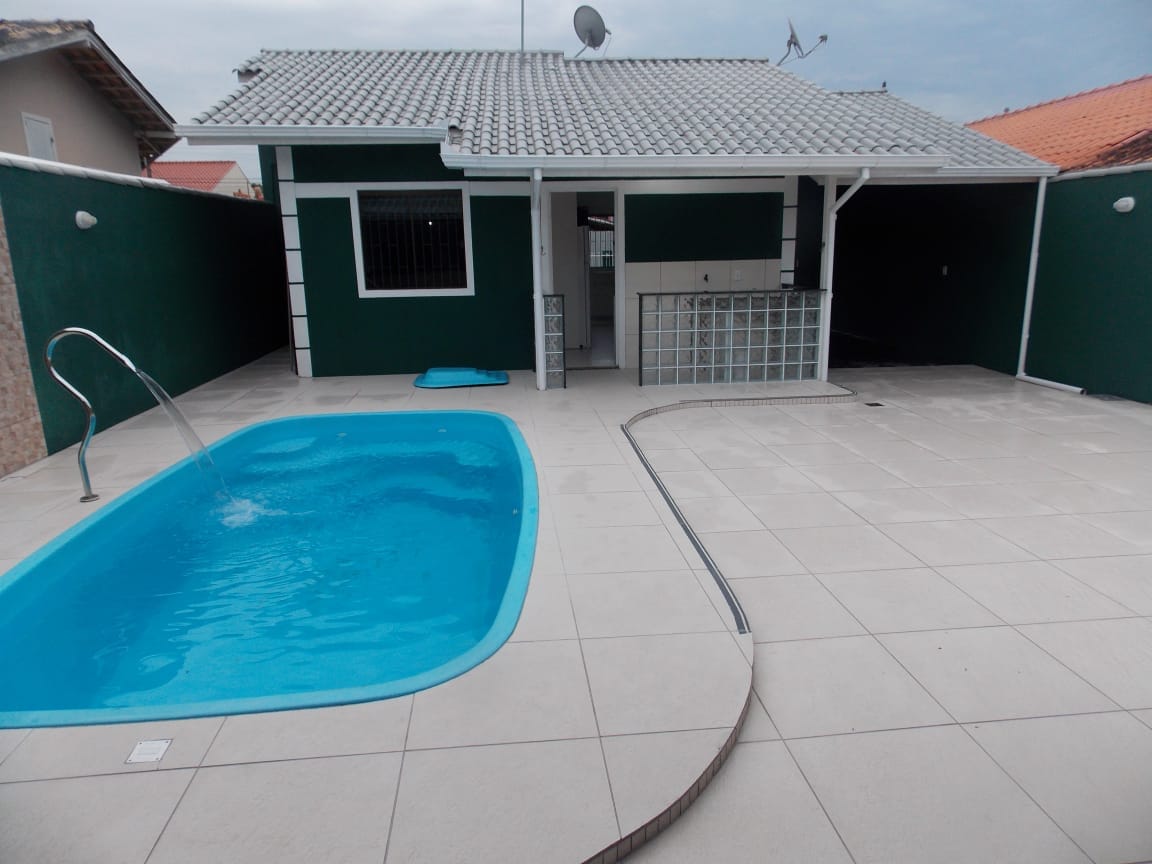An inviting outdoor area features a swimming pool alongside a tiled patio. A small waterfall flows into the pool, while the barbecue area is visible in the background. The walls are painted in a calming green, contributing to a serene setting.