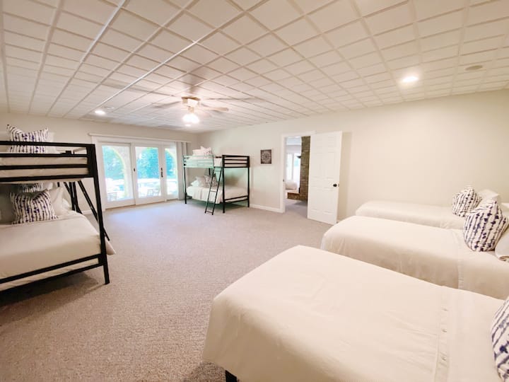 Walkout basement bunk room with en suite full bath, 3 single beds, 3 bunk beds, and patio access. 