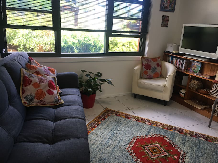 Light-filled living area with click-clack sofa as potential extra bed.