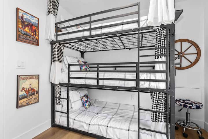 เตียงสองชั้น 3 หลังพร้อมผ้าม่านแบบกำหนดเองและโต๊ะทำงานวางใบไม้ติดผนังที่มุมขวา 