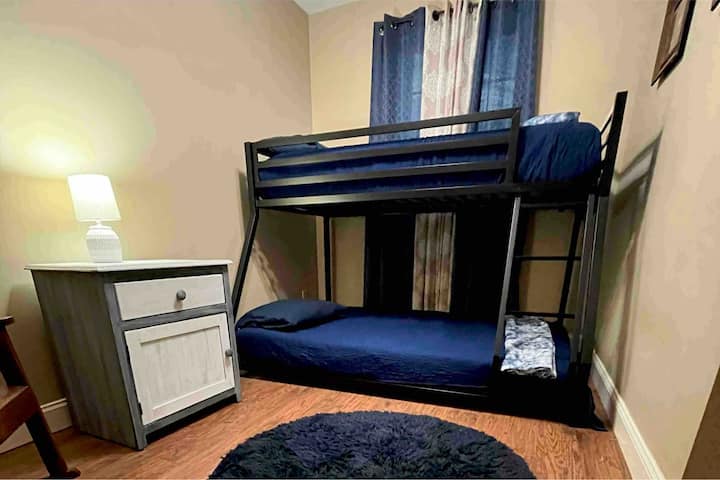 Chambre au rez-de-chaussée avec lits jumeaux superposés. Il y a également une salle de bains complète en bas. 