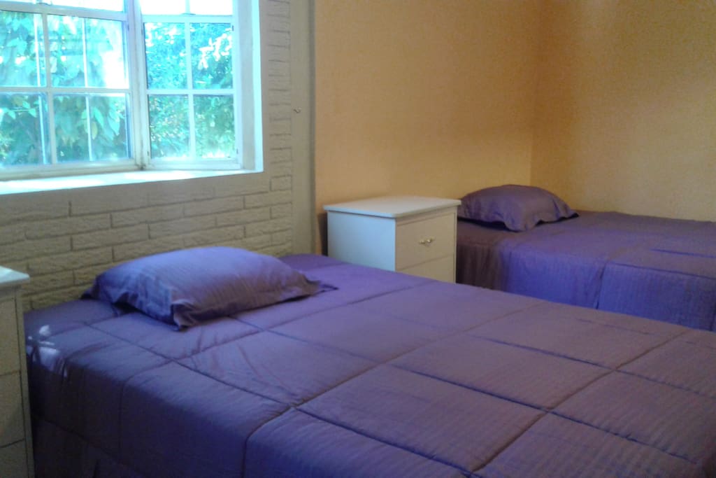 Double room with double beds, bedside tables, fan, closet.