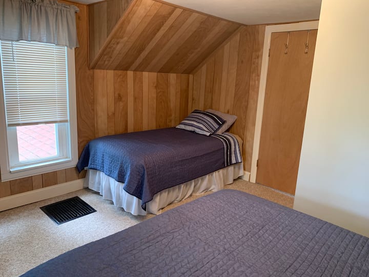 Habitación más grande en la planta superior con una cama tamaño queen y dos camas individuales.