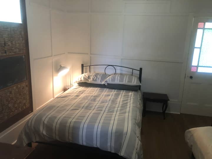 Cama doble en habitación compartida con puerta puesta en un porche cerrado 