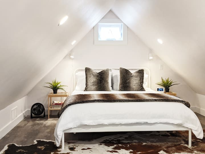 Our cozy bedroom is tucked under the low peaked ceiling. A plush Queen sized bed features bedside reading lights, alarm clock, portable Bluetooth speaker and an additional fan. 