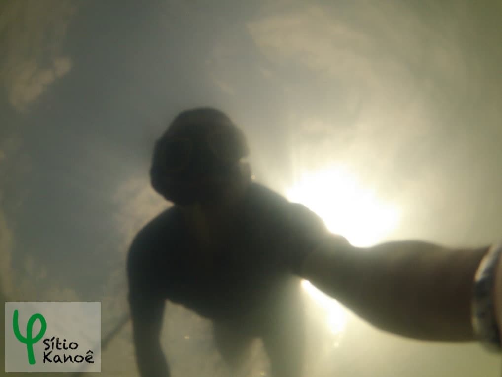 An underwater view captures a figure in snorkeling gear. The sunlight filters through the water, creating a shimmering effect. The clarity of the water allows for an unobstructed view of the swimmer's movements, enhancing the sense of exploration and tranquility.