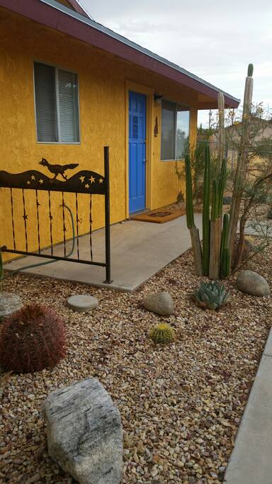 Front of house with cactus garden and metal roadrunner railing.
