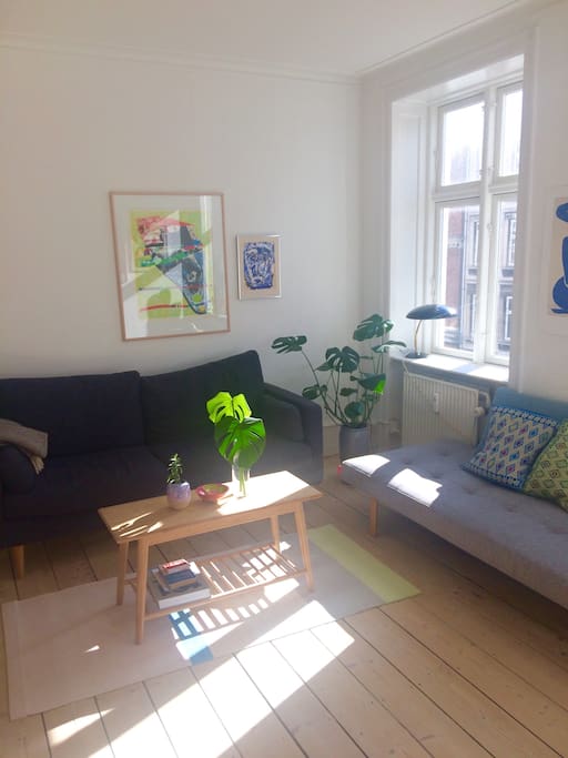 Big, bright and colorful living room with 2 couches and a lot of art on the walls.